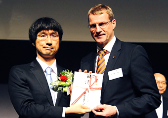 Kawano receiving the award certificate from a representative of the sponsoring companies