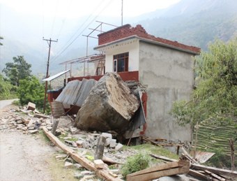 Massive rock dislodged from hill coming to rest against reinforced concrete building