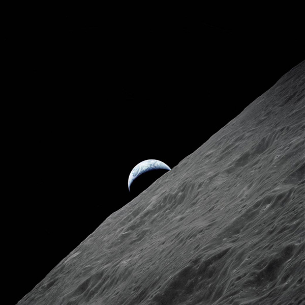 The crescent Earth rises above the lunar horizon in this spectacular photograph taken from the Apollo 17 spacecraft in lunar orbit during final lunar landing mission in the Apollo program.