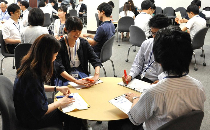 Staff members in groups of four around entakun, round cardboard tables used for brainstorming and discussion