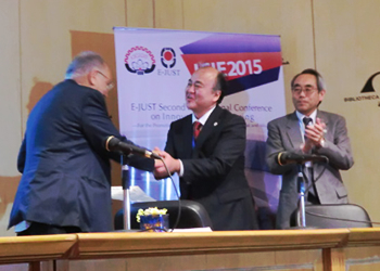 Professor Tanaka receiving a certificate and gift from the president of E-JUST