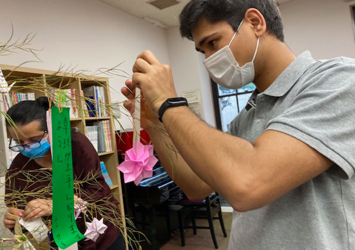 Gently attaching tanzaku strips to bamboo leaves