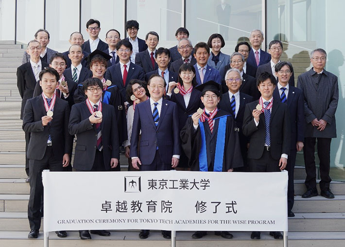 Graduates with their commemorative medals on stairs of Taki Plaza