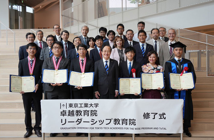 Graduates with their diplomas on stairs of Taki Plaza