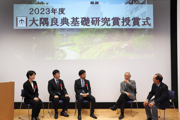 Three awardees and two presenters talking at the ceremony