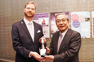 Mishima presenting bottle of sake to Nobel Museum