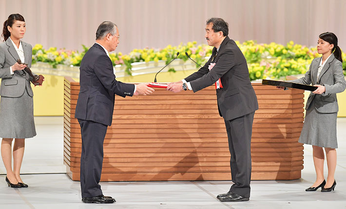 Executive Vice President for Research Ando (center right) receiving honorary certificate and commemorative gifts