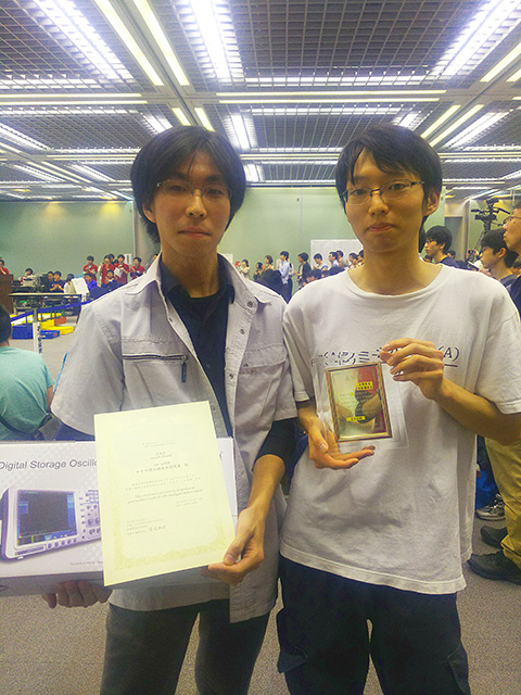 Chubachi (left) with certificate and prize, Suzuki holding winners’ plaque