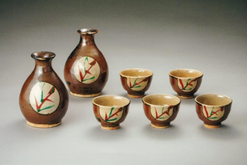 Sake decanters and cups with kaki glaze and red circle motif by Shoji Hamada, class of 1915