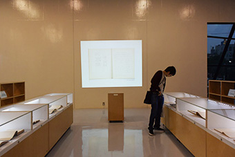 Well-bound notebooks on display (left), images of notebooks projected onto Museum wall (right)