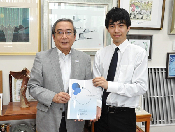 Then-President Mishima (left) receiving Student Survey recommendations from student representative Kojima