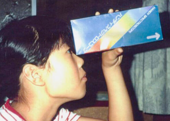 Prof. Takuwa using a prism tool. At the end of the box is a tiny hole. The entering light is separated into its spectrum of rainbow colors.