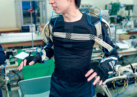 Tomoki Abe (2nd year master's student, Mechanical Engineering, School of Engineering), who appears on the cover, is wearing a special power suit created by a full-body 3D scan. Injecting air into artificial muscles raises his arm, even though his own muscles are relaxed. The initial goal is to provide support in tasks requiring extended periods of arm-raising, such as in manufacturing and agriculture, with the eventual goal of finding use in care and welfare.