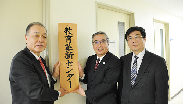 看板を掲げる松澤センター長と三島学長、丸山理事・副学長