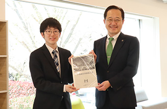 益学長へ提言書を提出する学生スタッフ代表の吉田さん（左）