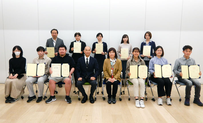認定証が授与された学生・教職員と、岡村哲至学生支援センター長（前列左から4人目）、道又紀子学生相談部門長（同5人目）