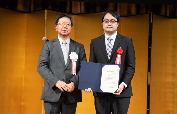 （左から）船井情報科学振興財団の船井哲雄理事長、褒賞式で賞状を授与された西早助教