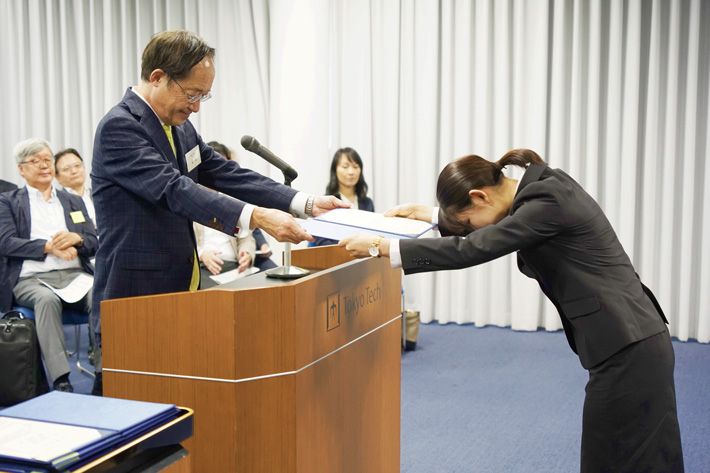 益一哉学長から奨学生証を授与される学生（右）