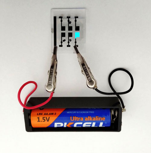 乾電池（1.5 V）1本で青色有機ELを光らせている写真