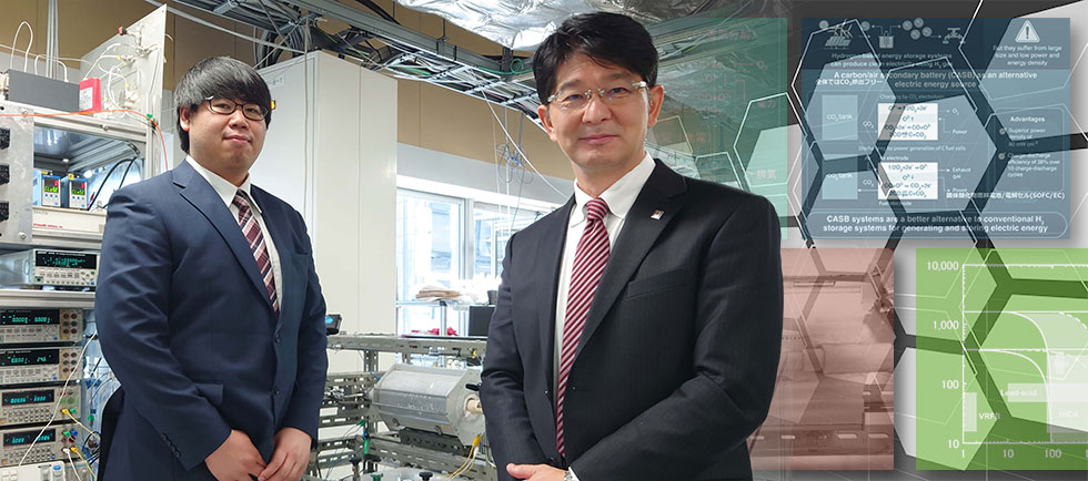 今回開発したCASBシステムの前で写真に納まる伊原学教授（右）と亀田恵佑さん（左）