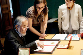 自身の賞状について説明を受ける大隅栄誉教授 © Nobel Media AB 2016. Photo: Alexander Mahmoud