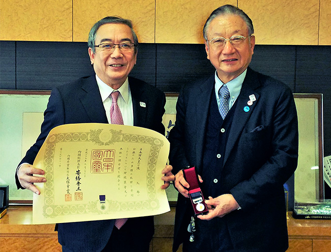 紺綬褒章を手にする滝氏（右）と三島学長（左）