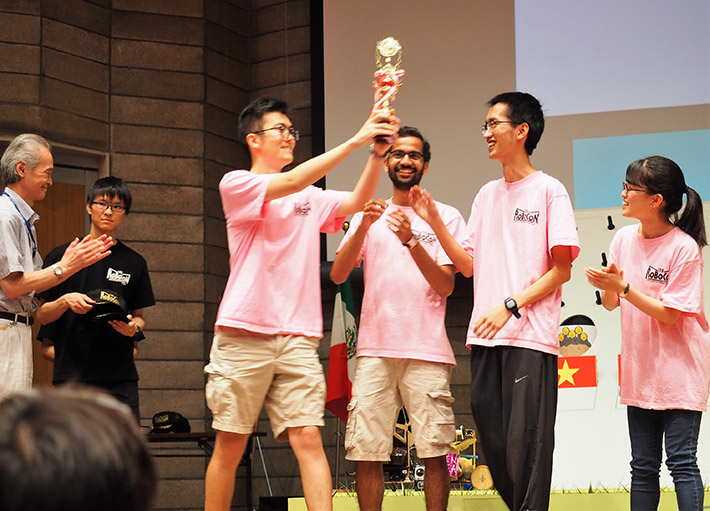 佐藤勲理事・副学長（企画担当、左端）から優勝トロフィーを受け取り喜ぶピンクチーム