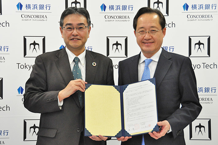 協定書を囲む横浜銀行の大矢恭好代表取締役頭取（左）と本学の益一哉学長（右）