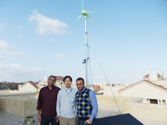 学生とともに講義棟の屋上に組み上げた風力・太陽光発電機（中央が大川原特任准教授）