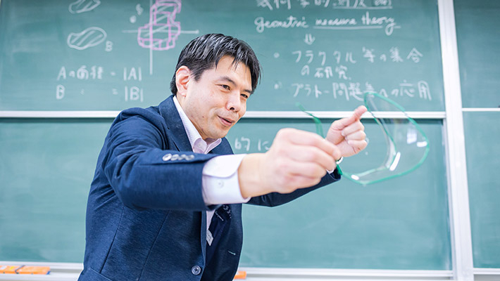 針金で作った枠を石鹸水に浸して持ち上げると、枠の中に石鹸膜ができる。石鹸膜はとても薄いため数学的な曲面と考えられる。